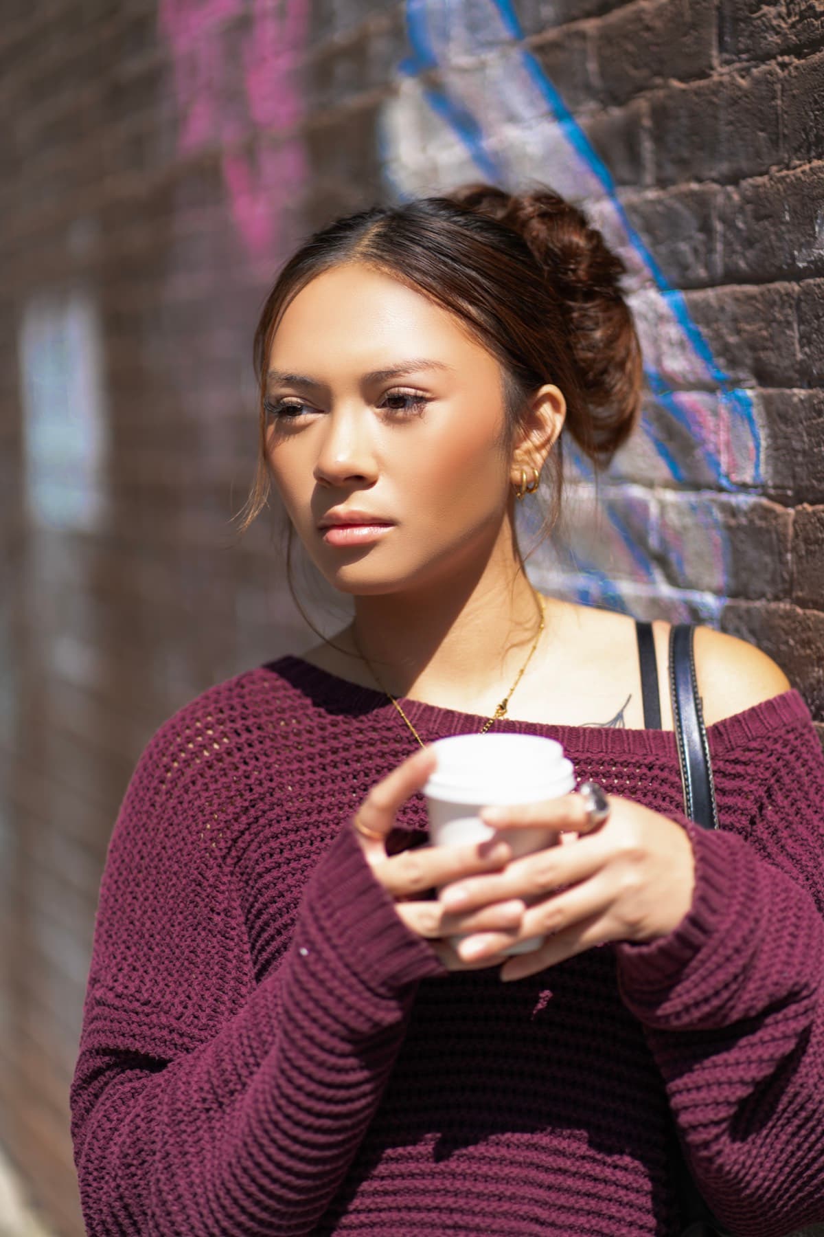 Outdoor portrait of a woman holding a paper cup in bright sunlight.